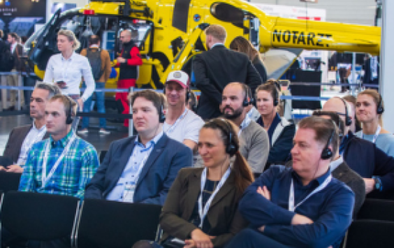 Attendees at European Rotors event with yellow helicopter on display behind