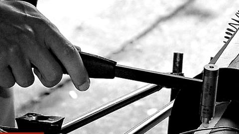 Engineer striking a structure with an impact hammer fitted with a sensor during a hammer impact test.