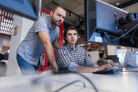 Two men working in office looking at computer screen