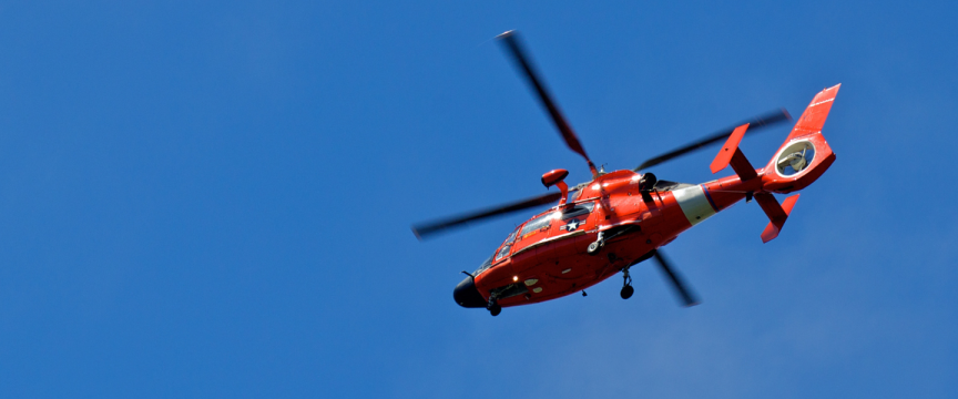 Red helicopter set against a clear blue sky