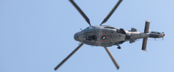Image of helicopter in the air. The shot is taken looking up at the underside of the aircraft