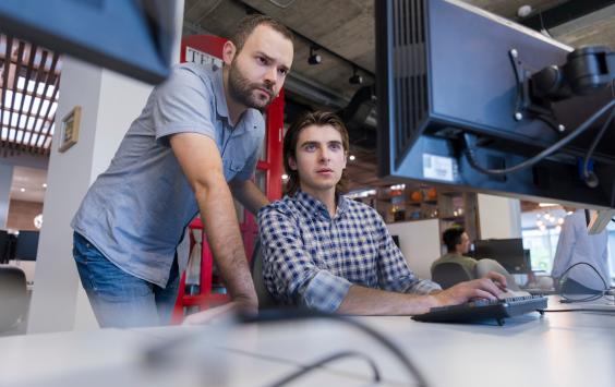 Two men working in office looking at computer screen