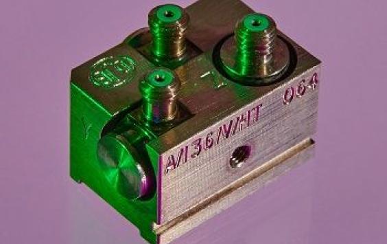 A grey rectangular cubed A/36 accelerometer shot in a purple background 