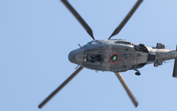 Image of helicopter in the air. The shot is taken looking up at the underside of the aircraft