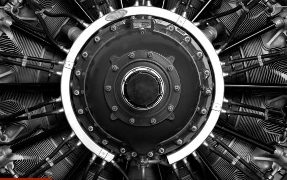 Front view of a radial aircraft engine with cylinders arranged around a central hub, in black and white.